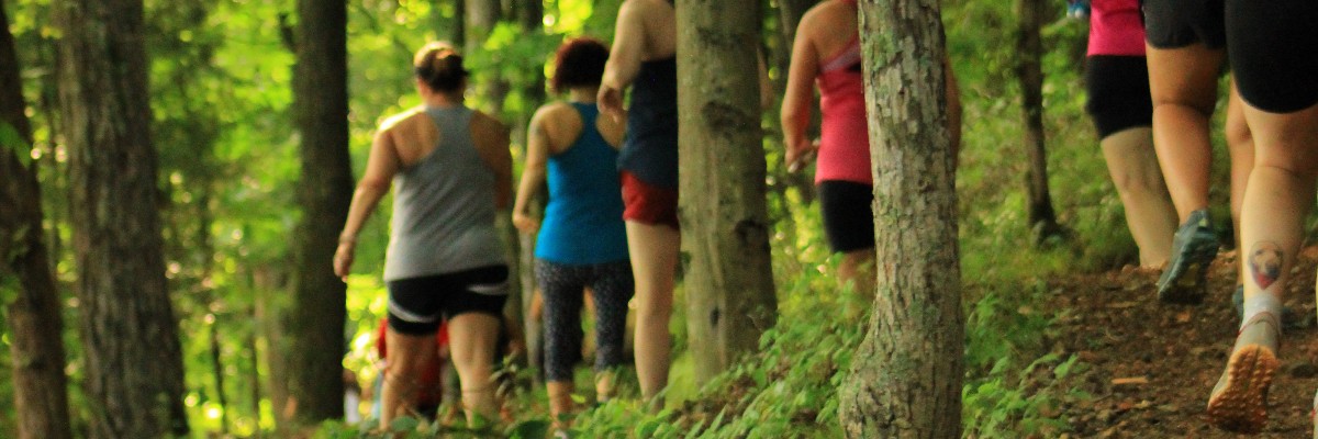 Women running in a race through a wooded area.