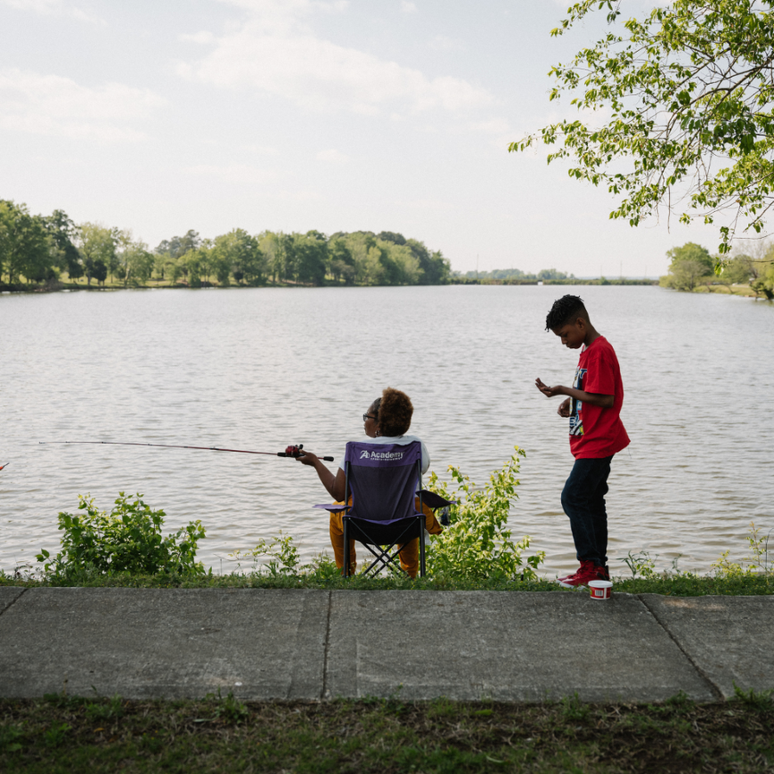 Two people fishing on a river side.