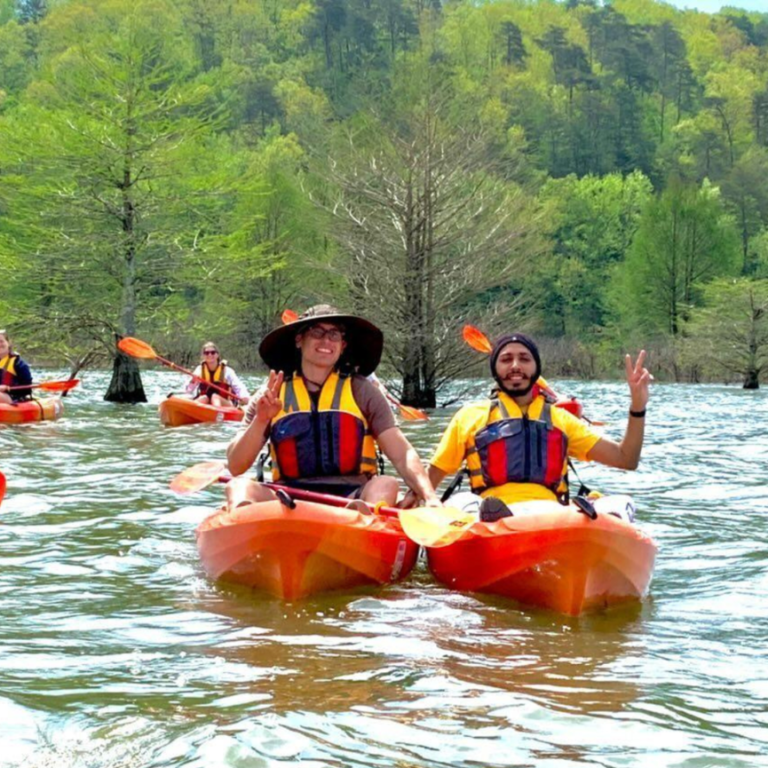 People on the river in kayaks, looking at the camera and grinning.