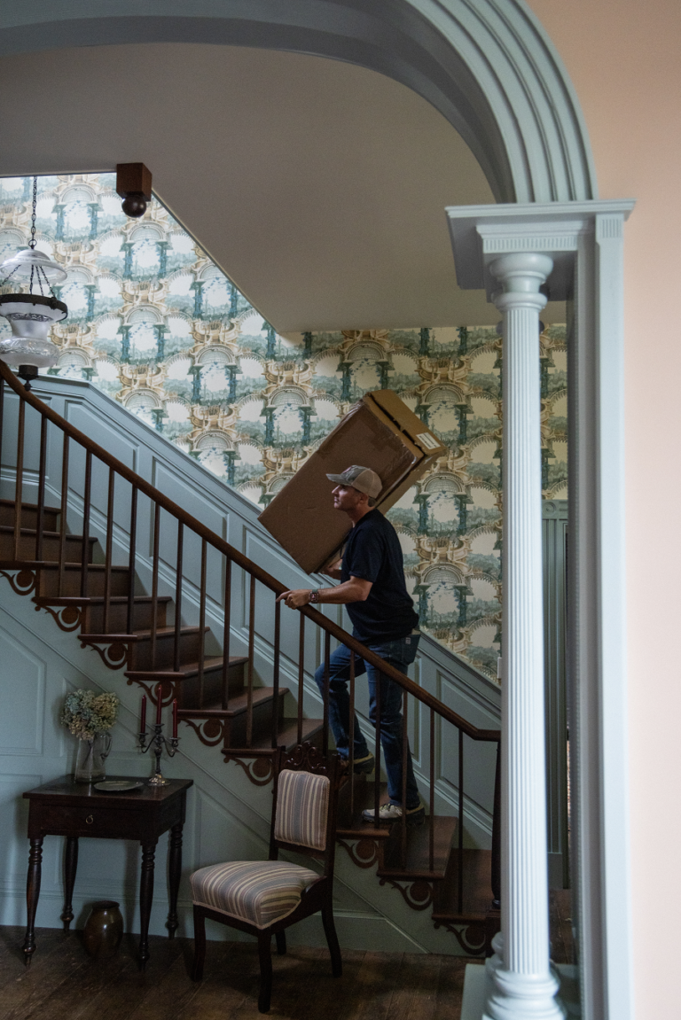A man climbing the stairs in the main hall of an historic house.